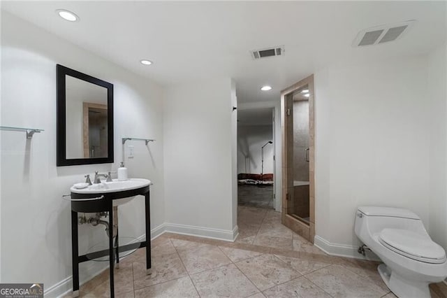 bathroom featuring sink, toilet, a shower with shower door, and tile patterned floors