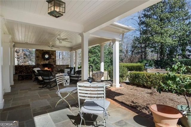 view of patio / terrace with ceiling fan and an outdoor living space with a fireplace