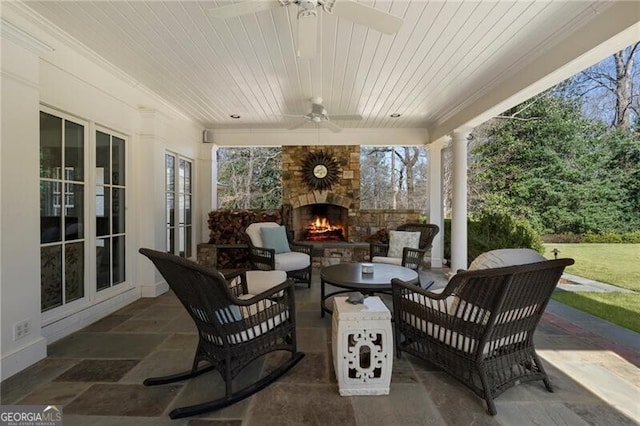 view of patio / terrace featuring ceiling fan and an outdoor living space with a fireplace