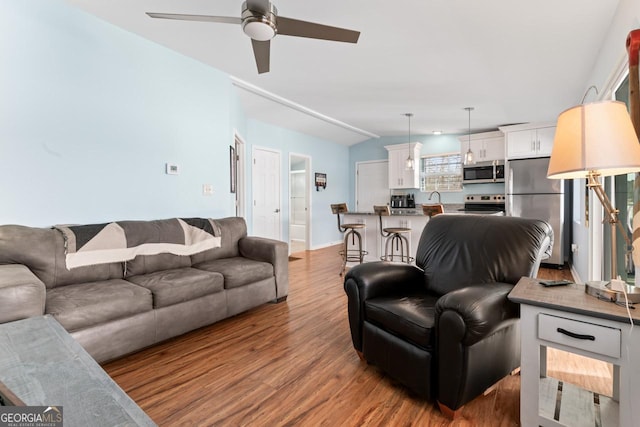 living room featuring ceiling fan, vaulted ceiling, and wood finished floors