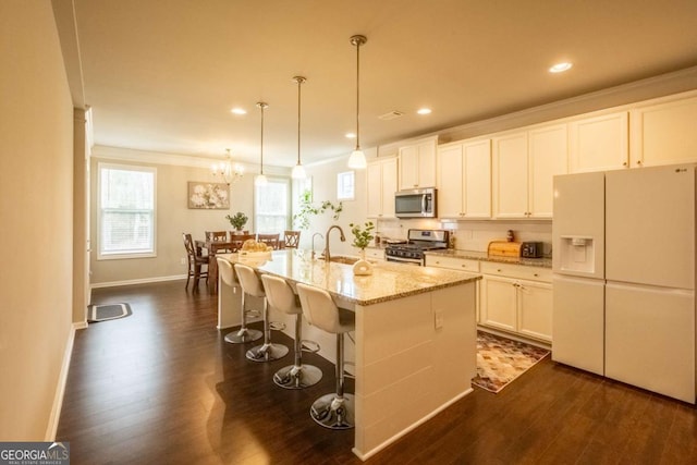 kitchen with a center island with sink, stainless steel appliances, white cabinetry, and hanging light fixtures