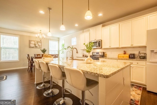 kitchen featuring white cabinetry, a center island with sink, appliances with stainless steel finishes, and pendant lighting