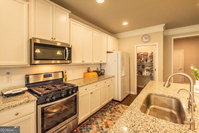 kitchen with sink, light stone counters, white cabinetry, crown molding, and stainless steel appliances