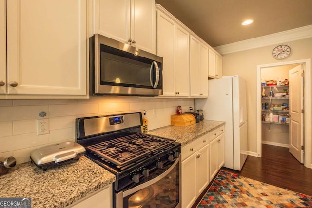 kitchen with white cabinets, appliances with stainless steel finishes, light stone counters, and ornamental molding