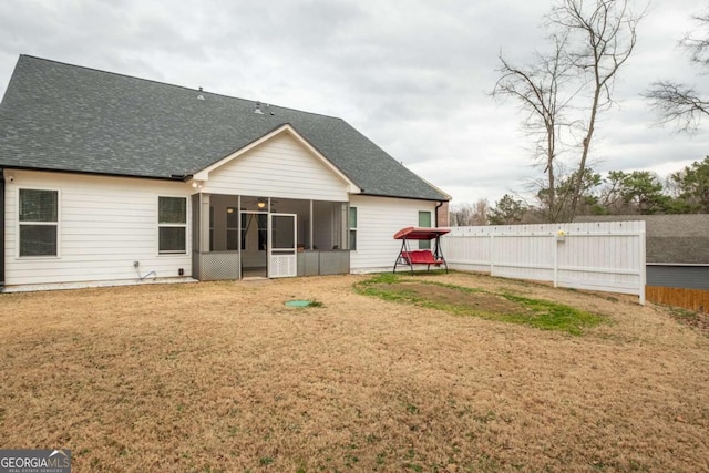 rear view of house featuring a yard and a sunroom