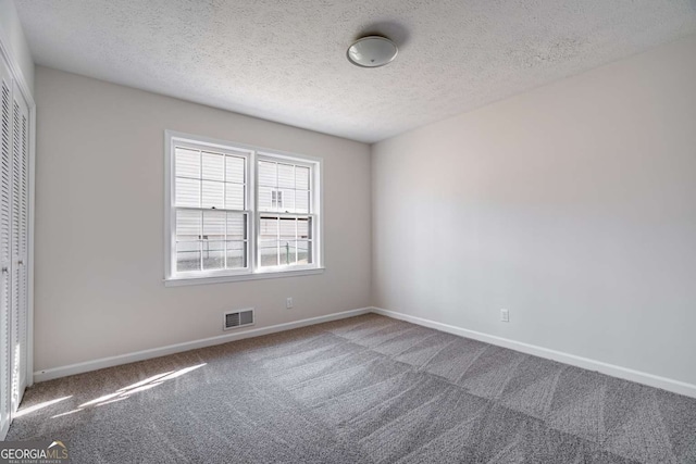 carpeted spare room featuring a textured ceiling