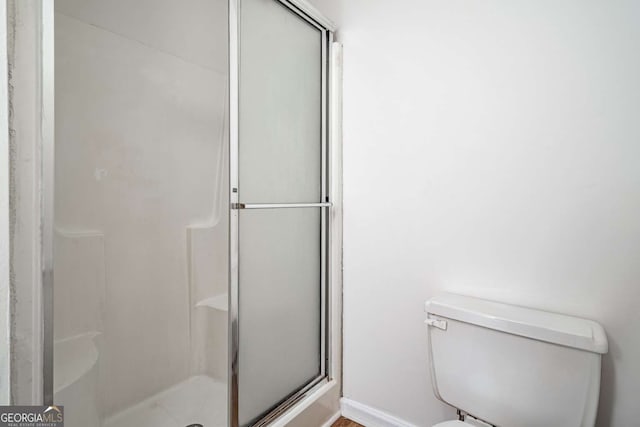 bathroom featuring toilet and a shower with shower door