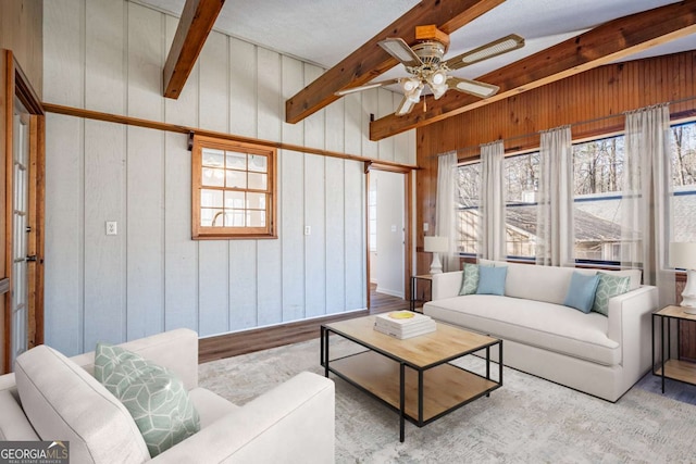 living room with light hardwood / wood-style flooring, wood walls, plenty of natural light, and beam ceiling