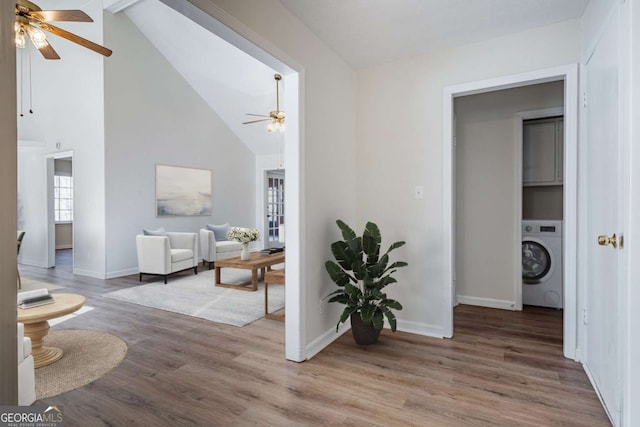 corridor with high vaulted ceiling, hardwood / wood-style floors, and washer / dryer