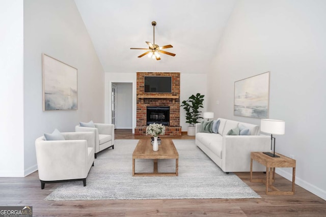 living room featuring ceiling fan, high vaulted ceiling, wood-type flooring, and a fireplace