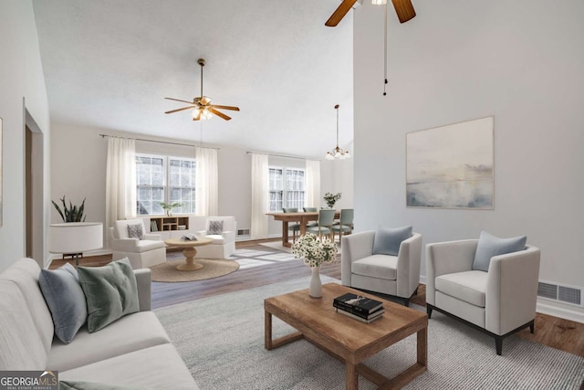 living room featuring ceiling fan with notable chandelier, high vaulted ceiling, and light hardwood / wood-style flooring