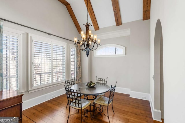 4080 Ryckeley Dr, Gainesville, GA 30504 - dining space featuring baseboards, lofted ceiling with beams, arched walkways, wood-type flooring, and a notable chandelier
