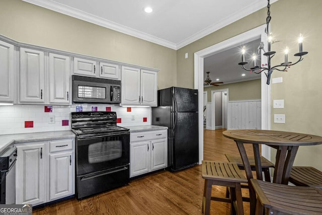 4080 Ryckeley Dr, Gainesville, GA 30504 - kitchen with light countertops, ornamental molding, ceiling fan with notable chandelier, black appliances, and dark wood-style flooring