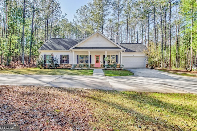 craftsman-style house featuring covered porch, a front yard, and a garage