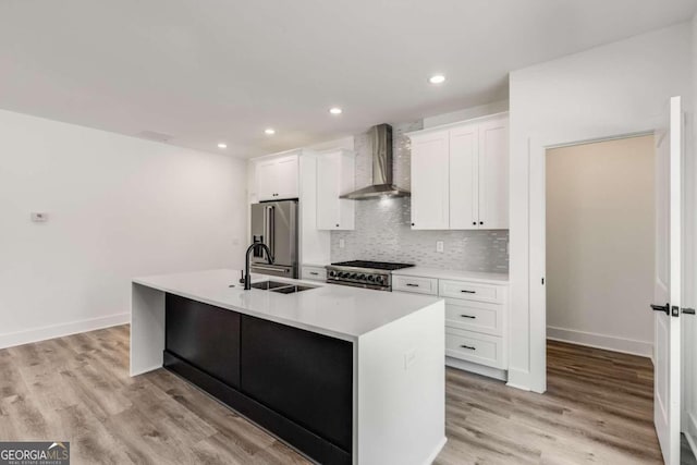 kitchen featuring an island with sink, white cabinetry, backsplash, wall chimney range hood, and high quality appliances