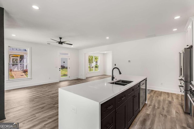 kitchen featuring a center island with sink, sink, dishwasher, and light wood-type flooring