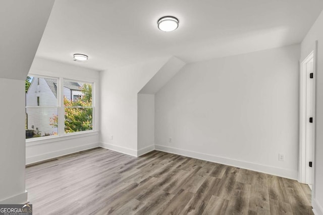 additional living space with light wood-type flooring and lofted ceiling