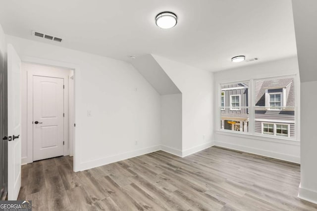 bonus room with hardwood / wood-style flooring and vaulted ceiling