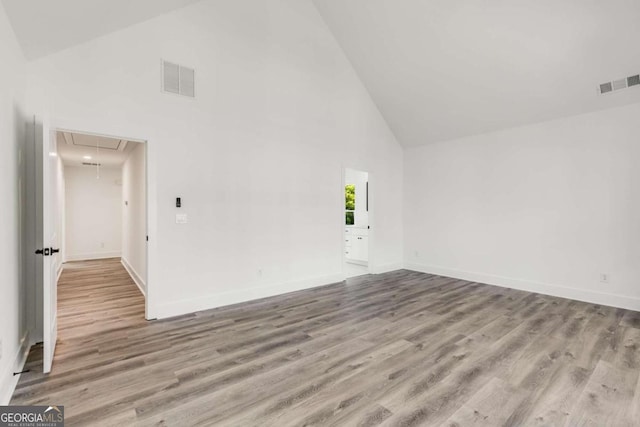 spare room featuring high vaulted ceiling and light wood-type flooring