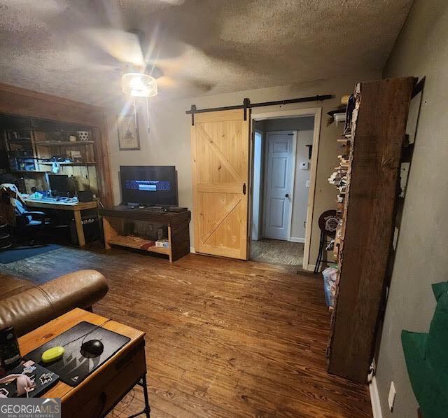 249 Ponderosa Ln, Barnesville, GA 30204 - living room featuring hardwood / wood-style floors, a barn door, and a textured ceiling