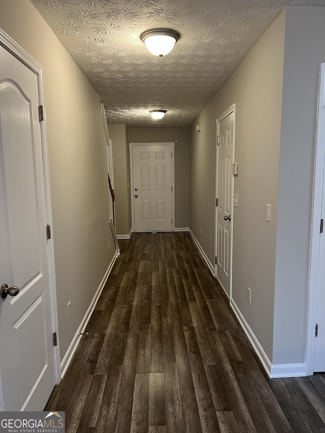 hallway featuring dark hardwood / wood-style flooring and a textured ceiling