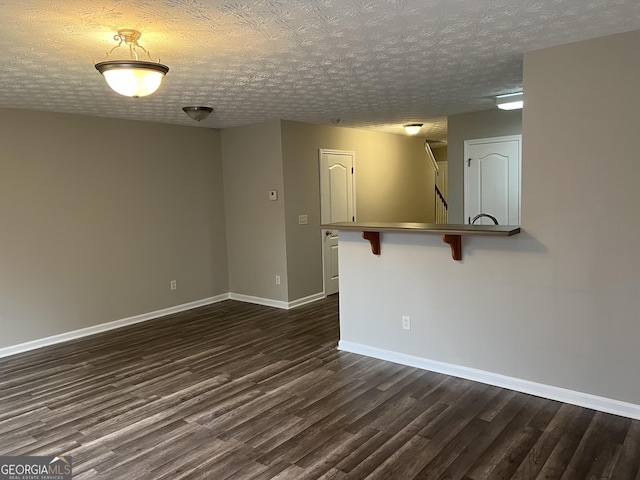 empty room with dark hardwood / wood-style flooring and a textured ceiling