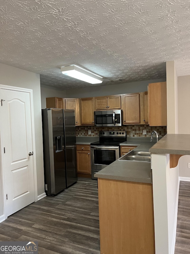 kitchen featuring kitchen peninsula, appliances with stainless steel finishes, dark wood-type flooring, and a kitchen breakfast bar