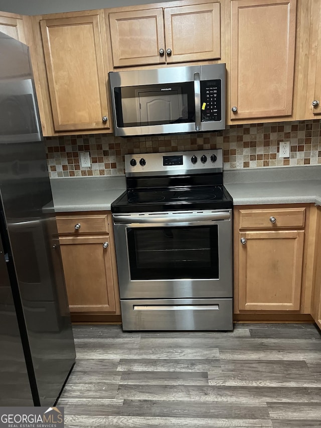 kitchen with hardwood / wood-style floors, appliances with stainless steel finishes, and backsplash