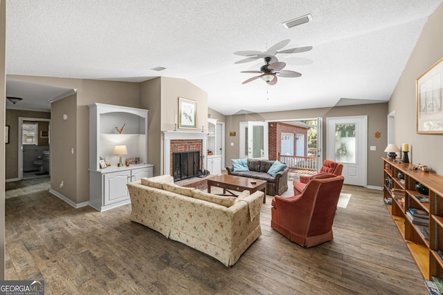 living room featuring a fireplace, lofted ceiling, a textured ceiling, and dark hardwood / wood-style flooring