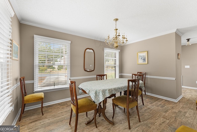 dining area with light hardwood / wood-style flooring, a chandelier, crown molding, and a textured ceiling