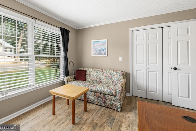 sitting room featuring light hardwood / wood-style floors, a textured ceiling, and ornamental molding