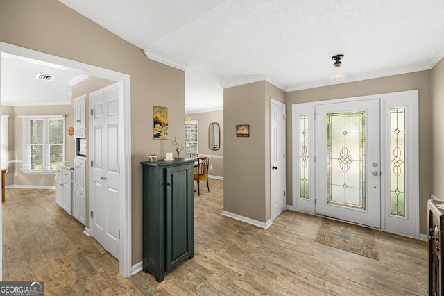 entrance foyer with light hardwood / wood-style floors, crown molding, and a textured ceiling