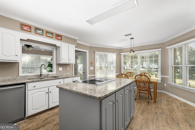 kitchen with hanging light fixtures, stainless steel dishwasher, black electric cooktop, sink, and white cabinetry