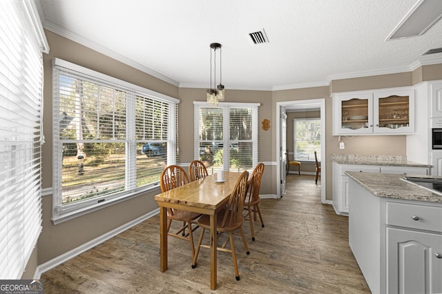 dining space with a textured ceiling, ornamental molding, and hardwood / wood-style floors