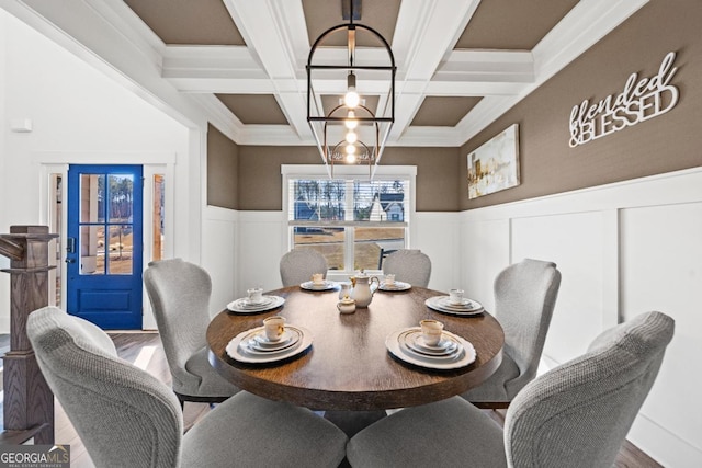 dining space with hardwood / wood-style floors, coffered ceiling, an inviting chandelier, and beamed ceiling