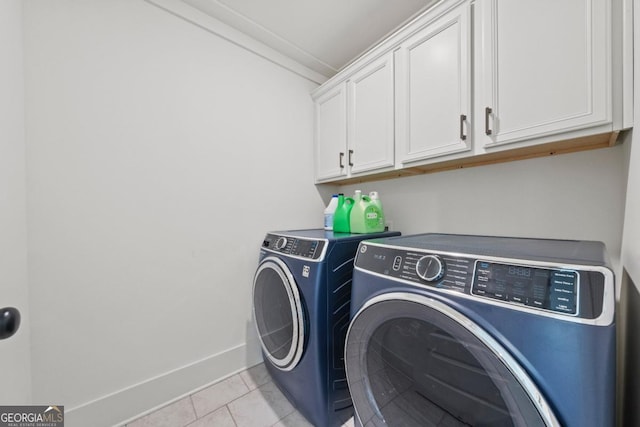 clothes washing area featuring cabinets, washer and clothes dryer, and light tile patterned floors