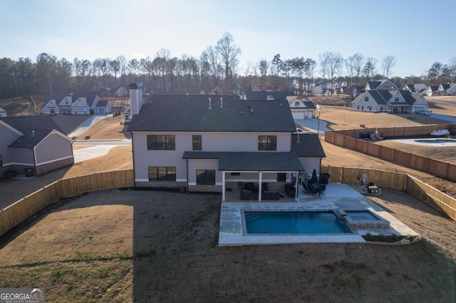 rear view of property with a fenced in pool and a patio area