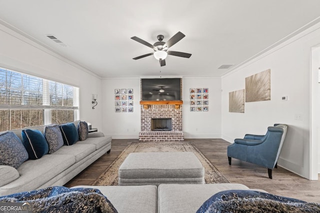 living room with ceiling fan, ornamental molding, a brick fireplace, and hardwood / wood-style floors