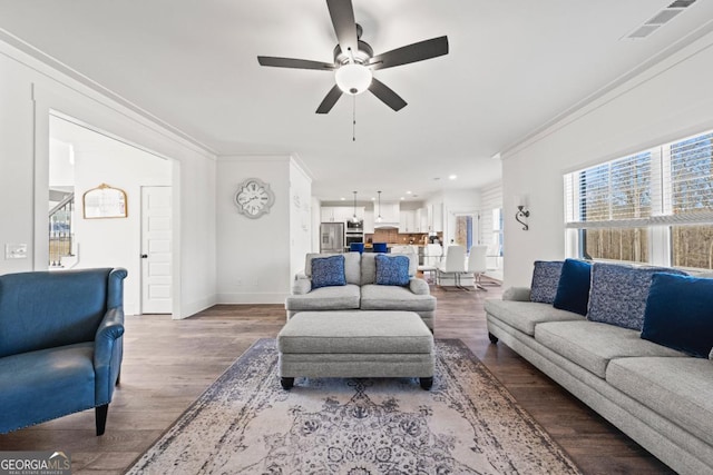 living room featuring ceiling fan, ornamental molding, and wood-type flooring