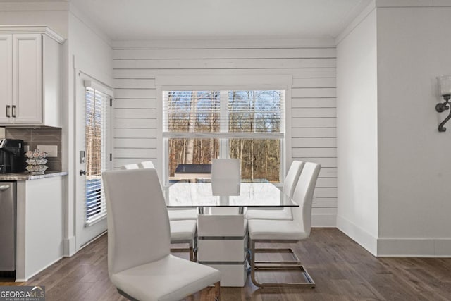 dining room featuring a wealth of natural light, crown molding, wood walls, and dark hardwood / wood-style floors