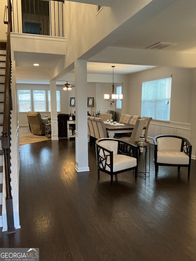 living area featuring a ceiling fan, visible vents, dark wood finished floors, and stairs