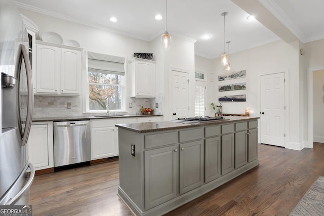 kitchen with white cabinetry, stainless steel appliances, a kitchen island, and sink