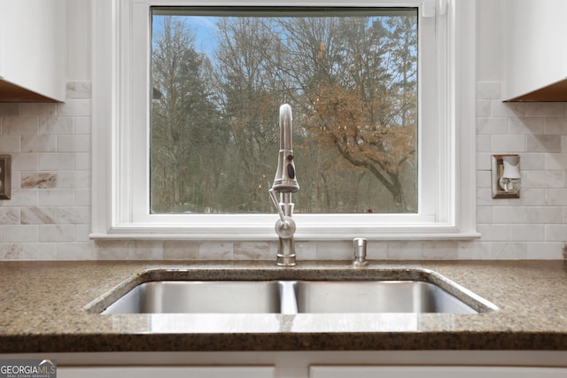 interior details with decorative backsplash, sink, and white cabinets