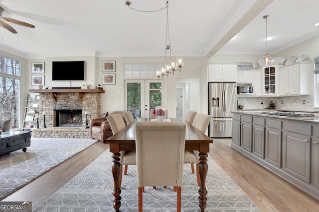 dining space featuring a fireplace, french doors, crown molding, and light hardwood / wood-style flooring