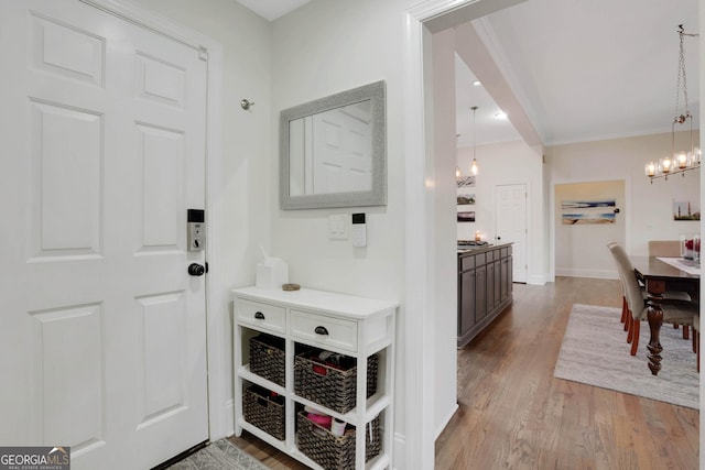 interior space featuring ornamental molding, a notable chandelier, and light hardwood / wood-style flooring