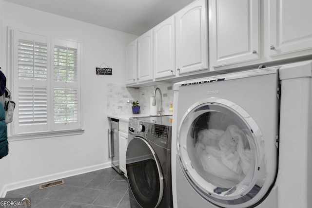 laundry room featuring washing machine and dryer, sink, cabinets, and dark tile patterned floors