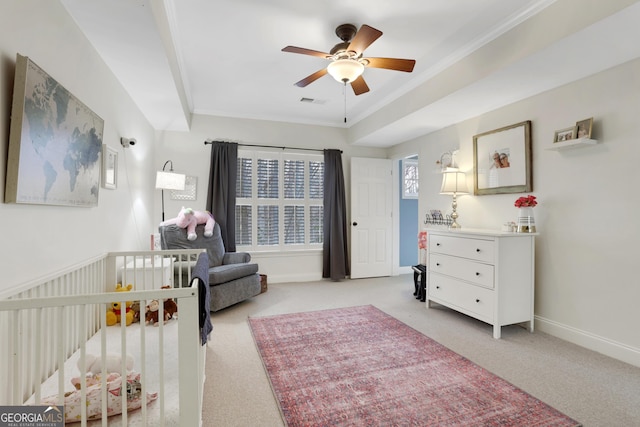 carpeted bedroom with a crib, crown molding, and ceiling fan