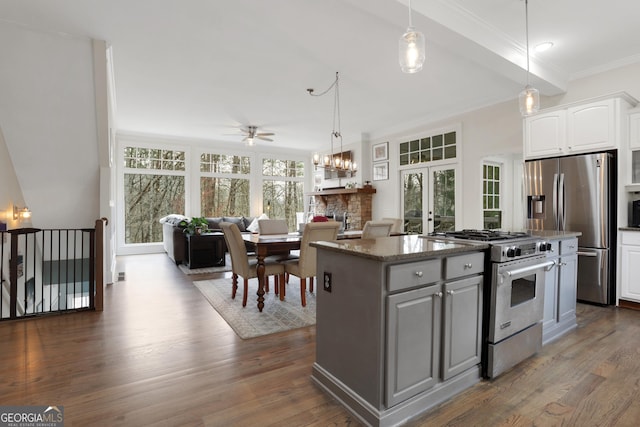 kitchen featuring stainless steel appliances, dark stone counters, a center island, ornamental molding, and white cabinetry