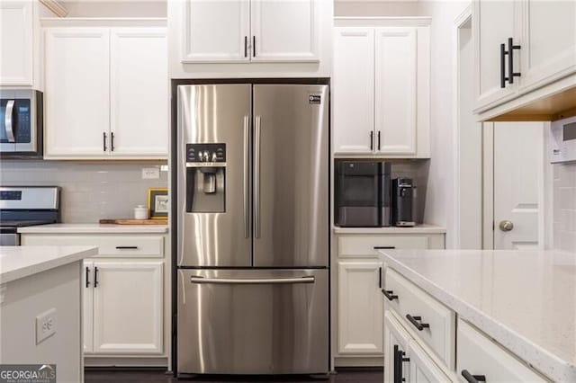 kitchen with appliances with stainless steel finishes, white cabinetry, backsplash, and light stone countertops