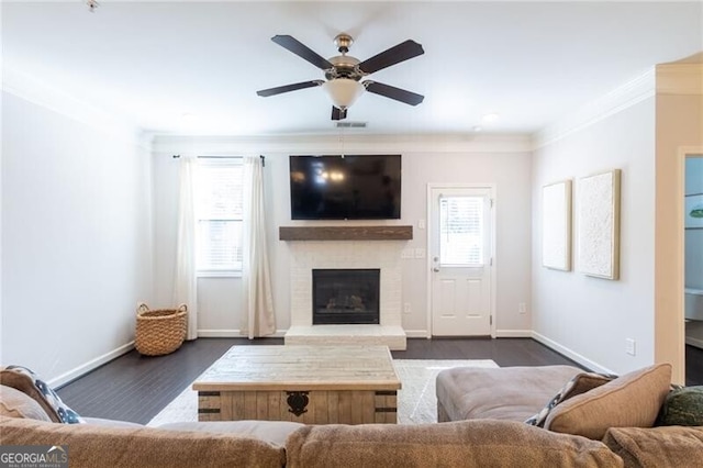 living room with ceiling fan, crown molding, dark hardwood / wood-style flooring, and a fireplace